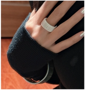 Detail of silver wavy textured wide band ring and matching striped bangle on model