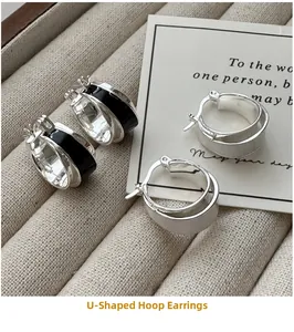 Detail view of U-shaped silver earrings with black enamel and brushed finish on a tray