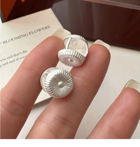 Macro detail of S925 sterling silver hoop earrings with radial texture and circular design