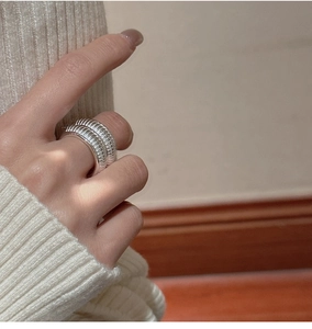 Close-up of a wide textured S925 sterling silver ring worn with a cozy knit sweater