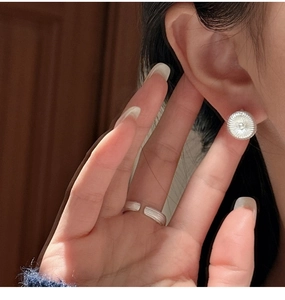 Detailed macro view of S925 sterling silver earrings and adjustable ring set on skin