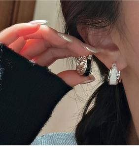 Close-up of S925 sterling silver earrings with black and white enamel drip on ear