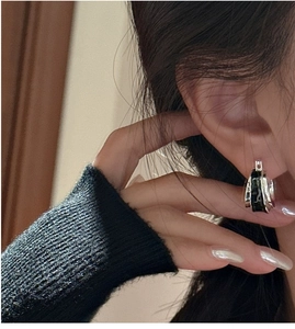 Close-up of S925 silver hoop earrings with black enamel and wavy texture on ear