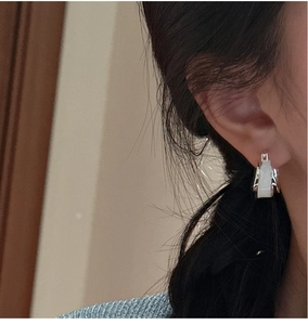 Close-up of S925 silver hoop earrings with white square stone on model ear