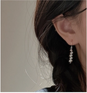 Detailed view of S925 silver dangling heart earrings worn by a model in soft light