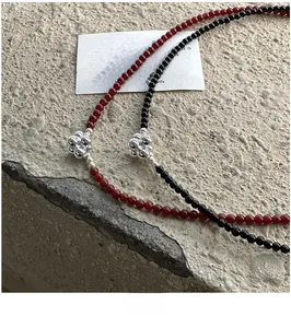 Detail of beaded S925 silver necklaces with red and black beads and flower pendants