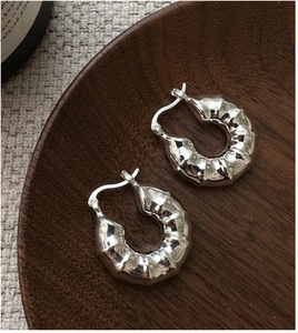 Détail de boucles d'oreilles créoles en argent S925 avec un design texturé en forme de vagues