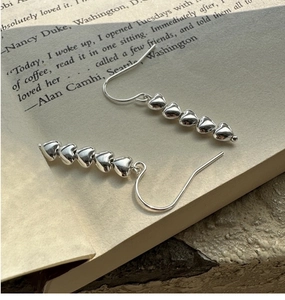 Detailed close-up of S925 sterling silver heart-shaped drop earrings on a vintage book
