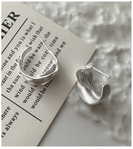 Macro detail of S925 sterling silver wavy earrings with matte finish on elegant card