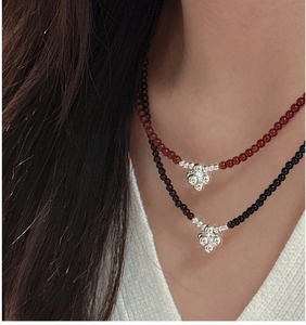 Detailed close-up of beaded S925 silver necklaces with floral pendants on a model