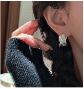 Detail view of irregular silver S925 earrings with a matte frosted finish on a model