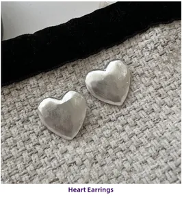 Macro detail of silver heart earrings featuring a premium brushed matte metal texture