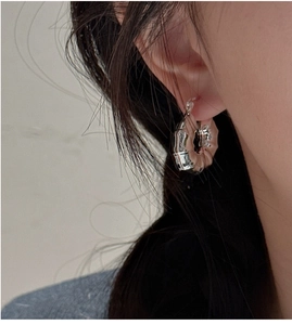 Détail d'une boucle d'oreille en argent à texture bambou portée par un modèle