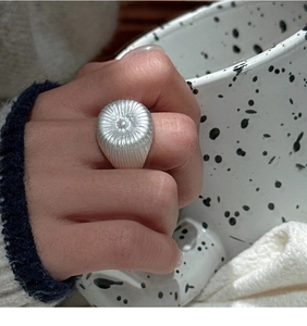 Gros plan sur une bague vintage en argent S925 avec textures radiales portée à la main