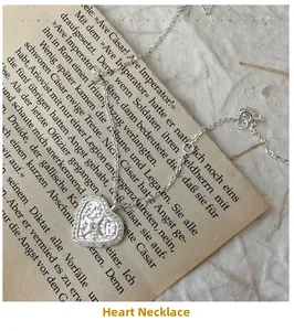 Macro detail of S925 silver heart necklace with star-set zircon on vintage paper