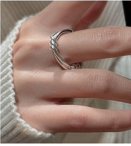 Macro shot of minimalist S925 sterling silver knotted ring on finger with white knit sleeve
