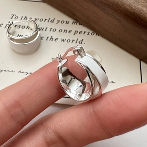 S925 sterling silver wide hoop earrings with white enamel finish on a wooden stand