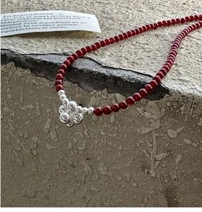 Detailed shot of red beaded S925 sterling silver necklace on a textured stone surface