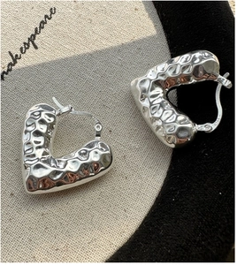 Dettaglio degli orecchini a cuore in argento S925 con texture lavica irregolare