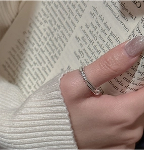 Detailed view of a silver minimalist twisted rope ring on a thumb with soft background