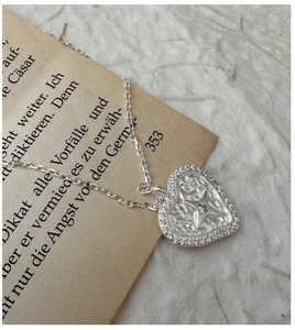 Macro shot of S925 sterling silver heart necklace with zircon on vintage book background