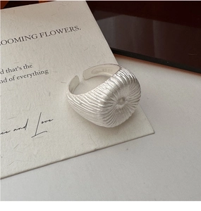 Gros plan sur bague en argent S925 avec texture radiale et finition mate brossée