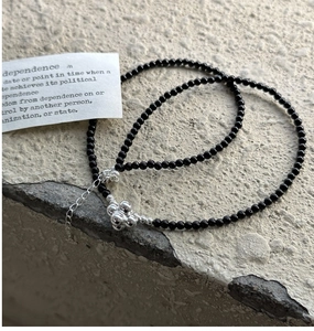 Detail of S925 silver beaded necklace with black beads and flower pendant on stone