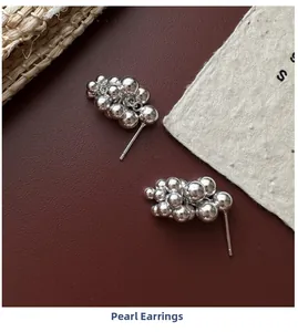 Detailed view of S925 sterling silver grape cluster earrings on dark red leather background