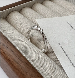 Macro shot of silver twisted spiral ring displayed inside a rustic wooden jewelry box