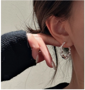 Detail of S925 sterling silver hoop earrings with a twisted rope design on an ear