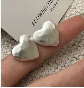 Macro view of matte S925 sterling silver heart earrings with brushed metal texture