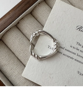 Close-up of S925 sterling silver knotted twist ring on a rustic wooden jewelry box