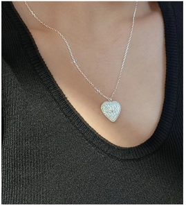 Detail of S925 sterling silver heart pendant with embossed patterns on black knitwear