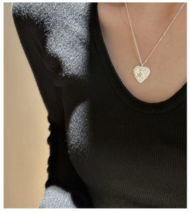 Close-up of S925 silver heart necklace with vintage patterns on a black sweater