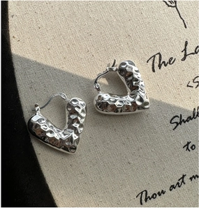 Primo piano dettagliato di orecchini a cerchio a cuore in argento S925 con texture martellata