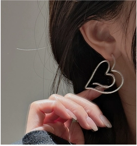 Detail of silver S925 heart earrings with unique hammered texture on a model side profile