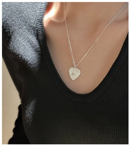 Detail of S925 sterling silver heart pendant with floral embossing and zircon stones