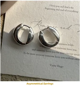 Close-up of S925 sterling silver irregular U-shaped hoop earrings on vintage paper
