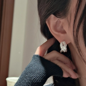 Elegant S925 sterling silver irregular wavy earrings on model in soft indoor lighting