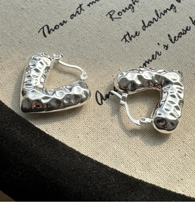 Dettaglio di orecchini a cuore in argento sterling S925 con trama martellata vintage