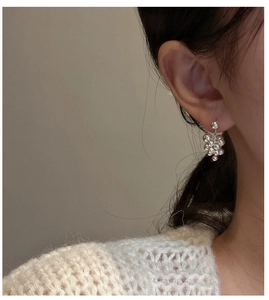 Detail of silver S925 grape bunch stud earrings on model with high polish metallic finish