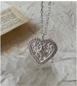 Macro shot of silver heart pendant with starburst engraving and cubic zirconia details