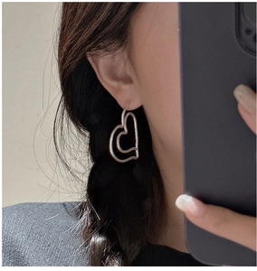 Detail of matte silver hollow heart earrings worn on ear showing vintage style