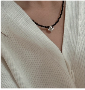 Close-up of S925 silver cross star pendant on a minimalist black onyx beaded necklace