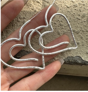 Macro detail of large matte S925 silver heart hoop earrings with textured finish