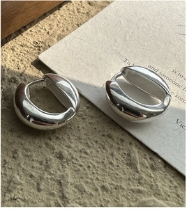 Close-up of chunky S925 silver U-shaped huggie earrings with polished mirror finish