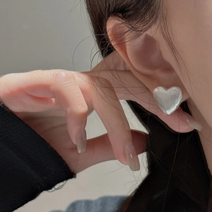 S925 sterling silver heart earrings with textured hammered finish worn by model