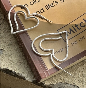 Detailed macro view of S925 sterling silver heart earrings with matte frosted texture