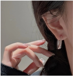 Gros plan d'un mannequin portant des boucles d'oreilles créoles en U argentées