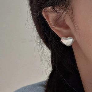S925 sterling silver heart stud earrings with matte hammered texture on model